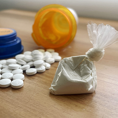 pill bottle with spilled pills and what powder in a bag