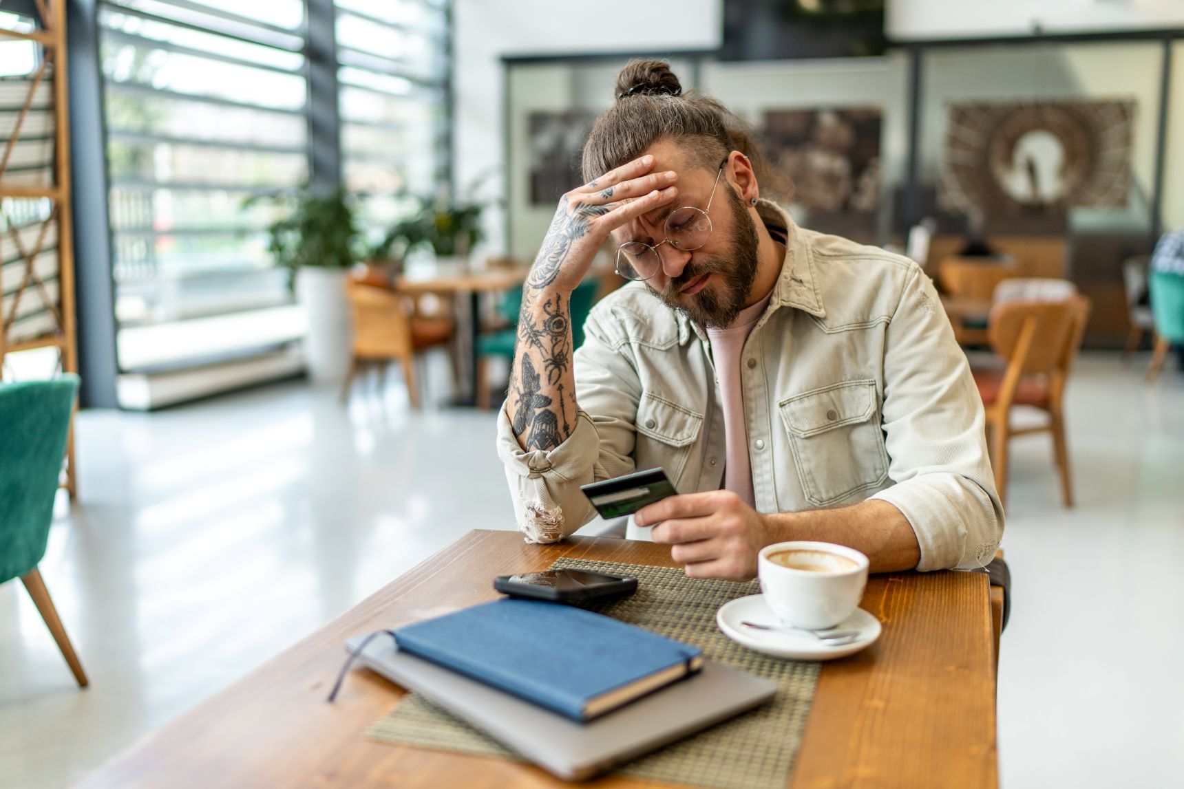 A young man sits at a table looking worried, representing some potential teen sports betting warning signs