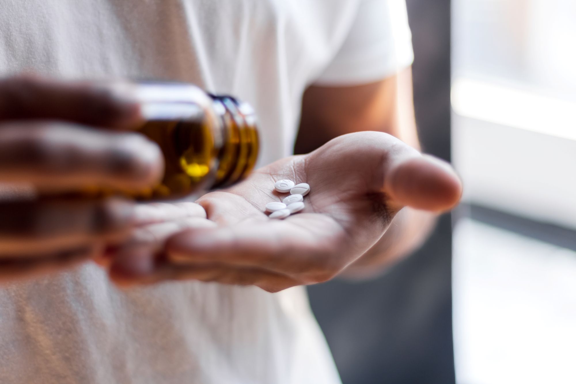 A person shaking pills out of a bottle, representing teen steroid use