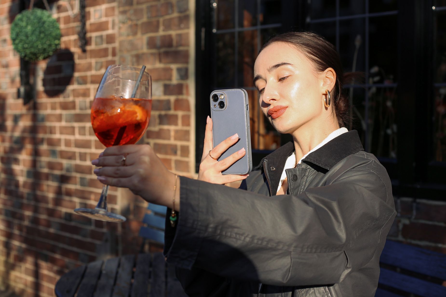 A teen takes a photo of a drink with her phone, representing social media and teen drinking