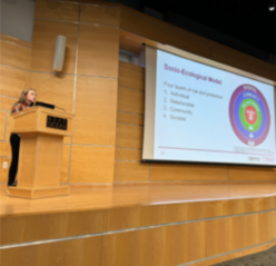 Cori standing at podium presenting at the COMPASS conference